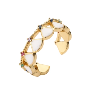 Macro shot of gold shell ring showing white enamel triangles and multicolored small crystals