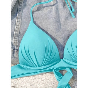 Detail of teal halter bikini top featuring pleated fabric texture and tie-neck design