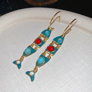 Close-up of articulated fish tassel earrings with colorful beads and vintage gold finish