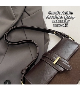 Detail of dark brown vintage crossbody bag with mixed textures and gold buckle