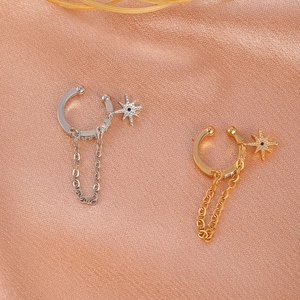 Detail von Kupfer-Zirkon-Sternohrclips mit Kettenanhängern auf rosa Seidenstoffhintergrund