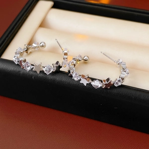 Macro shot of silver C-shaped star earrings with sparkling cubic zirconia on black leather
