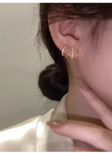 Close-up of a layered gold-plated hoop earring with pavé zircon accents on a model's ear