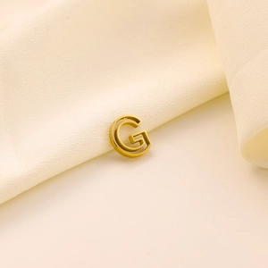 Gros plan d'un pendentif lettre G doré 18 carats sur un fond luxueux de soie crème