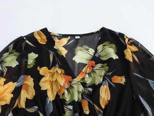 Dettaglio dello scollo a V su abito in chiffon a fiori con etichetta taglia S su nero