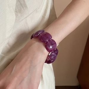 Detail of purple marble acrylic resin bracelet with white swirls on a woman's wrist