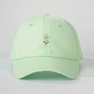 Détail de la broderie marguerite blanche et des coutures sur la casquette vert menthe