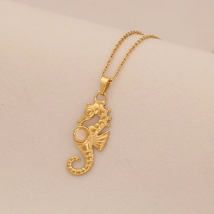 Golden sea horse pendant necklace with opal stone on minimalist pink textured background