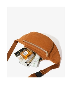 Detail view of brown corduroy waist bag interior with perfume, lipstick and phone