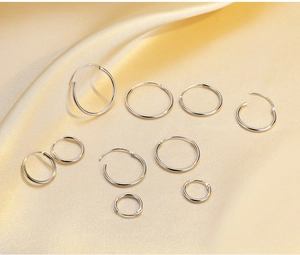Detailed view of assorted S925 sterling silver hoop earrings on elegant golden silk fabric