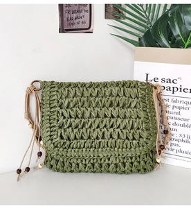 Detail of green handmade straw bag with decorative wooden beads and natural woven texture