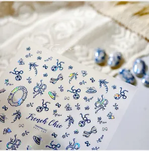 Macro view of blue butterfly bow nail stickers with holographic laser finish on white lace