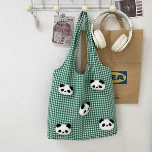 Detail of green checkered canvas tote with cute plush panda heads and soft fuzzy texture