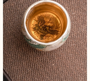 Detailed top view of a ceramic teacup with gold glaze and black dragon pattern