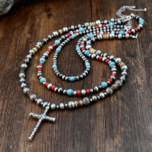 Ethnic bohemian turquoise beaded necklace with silver cross pendant on wooden surface