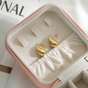 Gold water drop earrings with irregular textured surface in a pink jewelry box