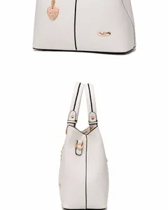 Detail view of cream white tote bag featuring heart charm and gold-tone hardware