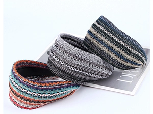 Close-up of three knitted headbands in striped patterns on a magazine with soft lighting