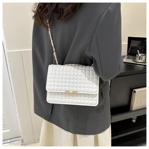 Dettaglio della borsa trapuntata bianca con catena dorata indossata da modella in posa chic