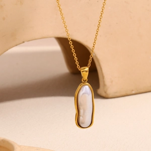 Gros plan d'un collier en perle baroque avec bordure plaquée or 18 carats sur chaîne