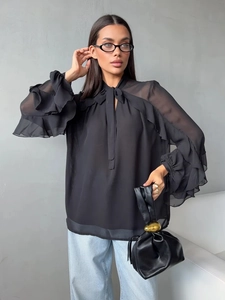 Detail of elegant black chiffon blouse featuring tiered ruffle sleeves and a bow tie neckline