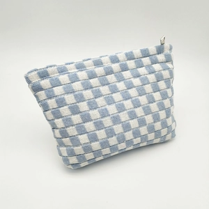 Macro detail of blue and white checkered knit fabric with a smooth silver zipper closure
