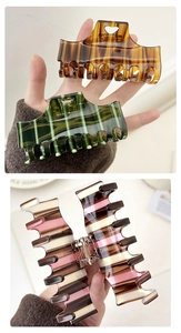 Detailed view of checkered claw clips in amber, dark green, and multicolor patterns