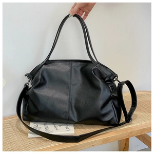 Detalle de bolso tote de cuero negro con grabado de lichi y herrajes de metal oscuro