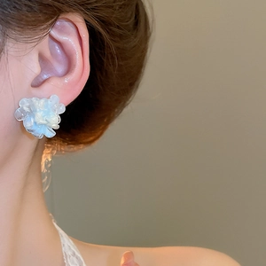Close-up of elegant 3D white flower stud earrings worn by a model for a chic look