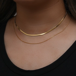 Detail of layered 18K gold plated herringbone and delicate round chain necklaces