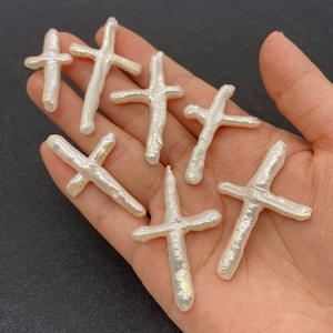 Irregular white Baroque pearl cross pendants with rainbow luster on a palm for jewelry DIY