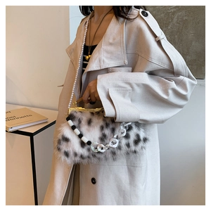 Sac en fausse fourrure à pois avec perles et chaînes porté sur un trench-coat chic