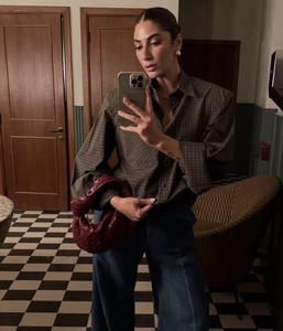 Mirror selfie showing a burgundy woven leather handbag paired with a plaid shirt
