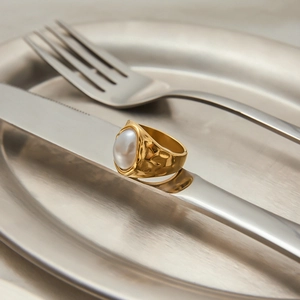 Detail of 18K gold-plated hammered ring with large baroque pearl on silver cutlery