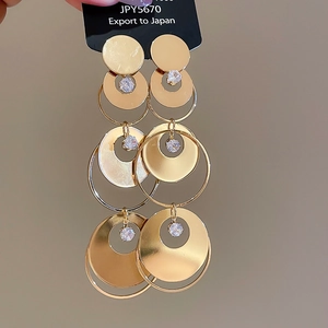 Macro detail of three-tier gold-plated drop earrings with clear crystal accents
