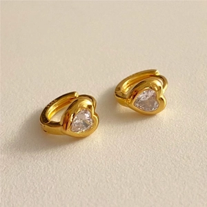 Macro detail of S925 sterling silver gold heart earrings with sparkling cubic zirconia