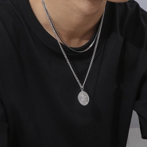 Close-up of double-layered silver chain necklace with oval medallion pendant on model
