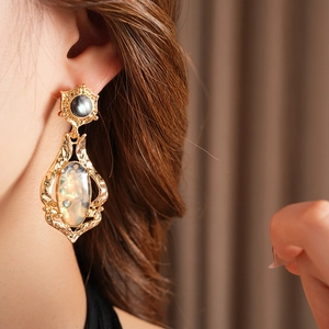 Gros plan de boucles d'oreilles vintage dorées avec pierre sombre et nacre irisée