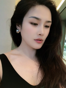 Close-up of model wearing geometric gunmetal pearl earrings with 18K gold trim