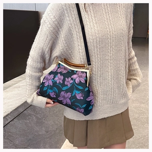 Close-up of vintage embroidery handbag with purple floral patterns and wooden handle