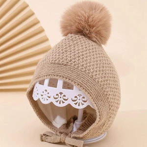 Nahaufnahme einer warmen khaki Strickmütze für Babys mit Bommel und Innenfutter