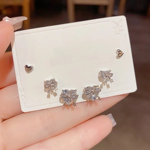 Close-up of three-piece set with silver bow heart stud earrings and sparkling zircon stones
