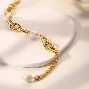 Detail of vintage freshwater pearl and gold oval link chain bracelet on a white stand
