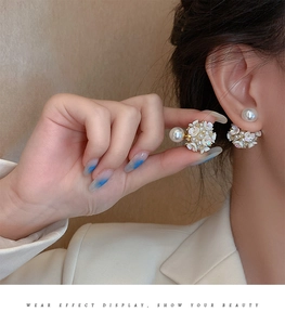 Detail view of white flower pearl earrings showing size and fit on a model's ear