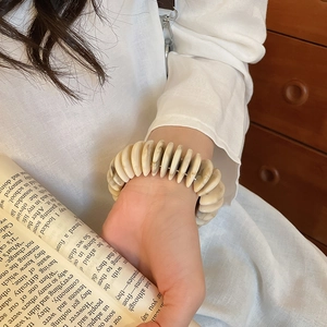 Detail of minimalist acrylic stretch bracelet with ivory marble texture on a female wrist