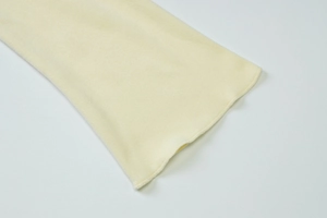 Close-up of fine overlock stitching on beige velvet cardigan fabric with soft texture