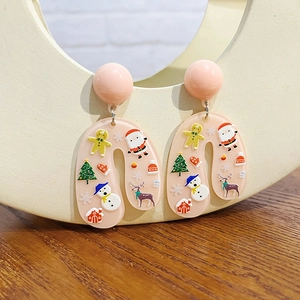 Macro detail of Christmas cartoon earrings featuring Santa and snowman patterns