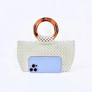 Detail of handmade pearl beaded handbag featuring brown resin ring handles and size scale