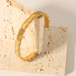 Detailed close-up of 18K gold-plated knotted bracelet featuring woven texture on stone