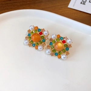 Macro shot of vintage style earrings with colorful rhinestones and faux pearls on a tray